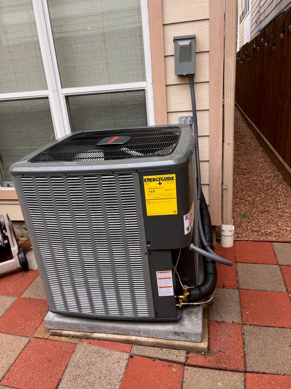 Air conditioning unit installed outside a home, showcasing energy efficiency rating.