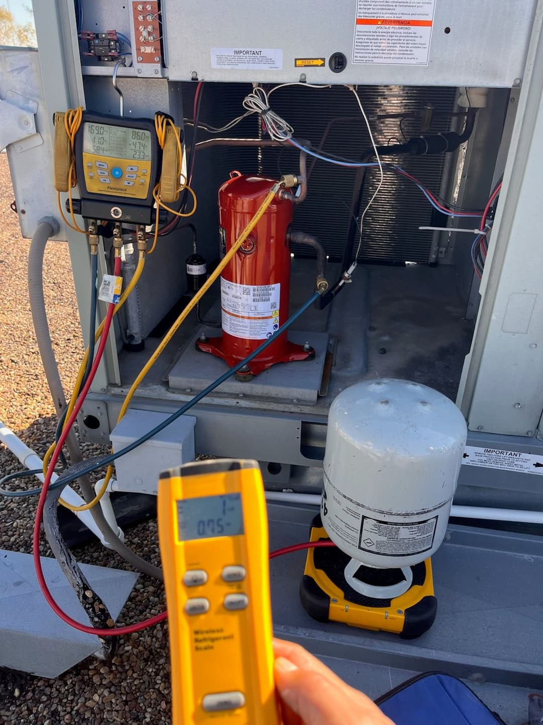 Technician measuring temperature on HVAC unit with digital thermometer and gauges.