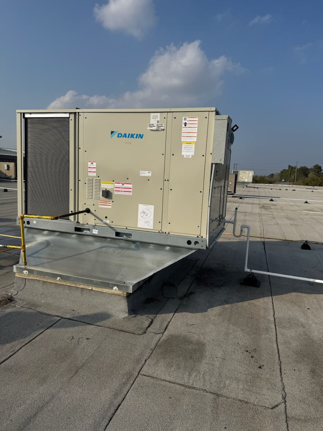 Daikin rooftop HVAC unit on a flat commercial building roof under a blue sky.