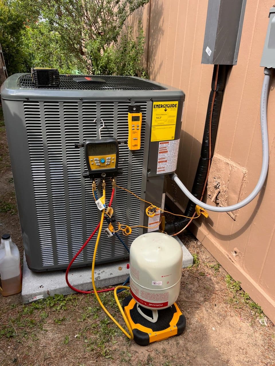 Outdoor air conditioning unit with gauges and propane tank for maintenance.