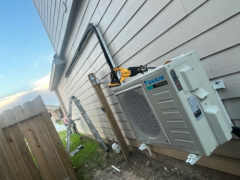Daikin air conditioning unit installed outside a house with tools and ladder nearby.